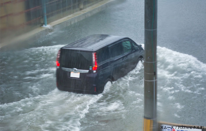 冠水した道路を走る車の写真